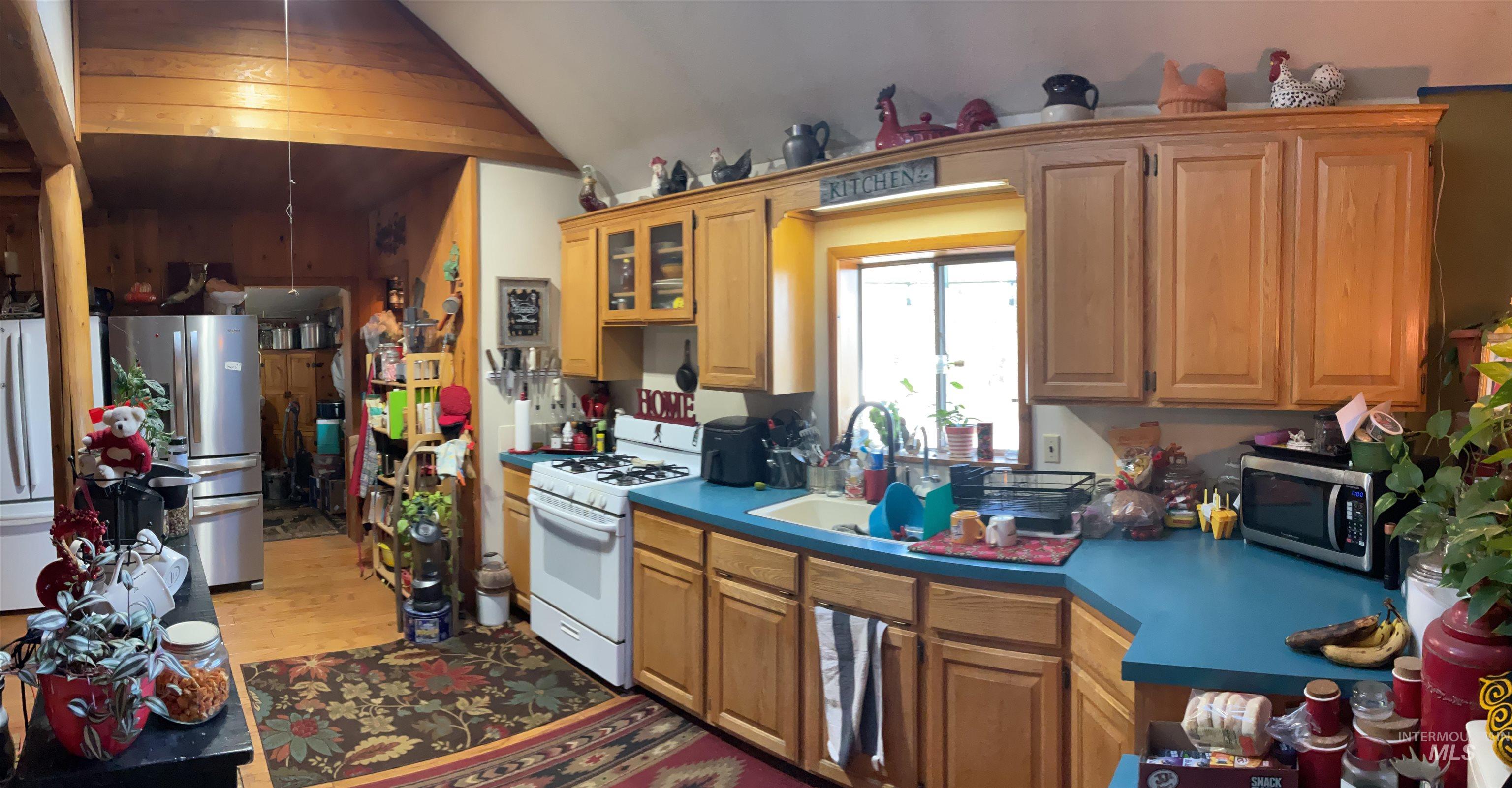176 West Buffalo Gulch Road Elk City, ID 83525 - Photo 11 of 38 Kitchen featuring light wood cabinetry, a white gas range, a white sink, and a window with a bright yellow frame