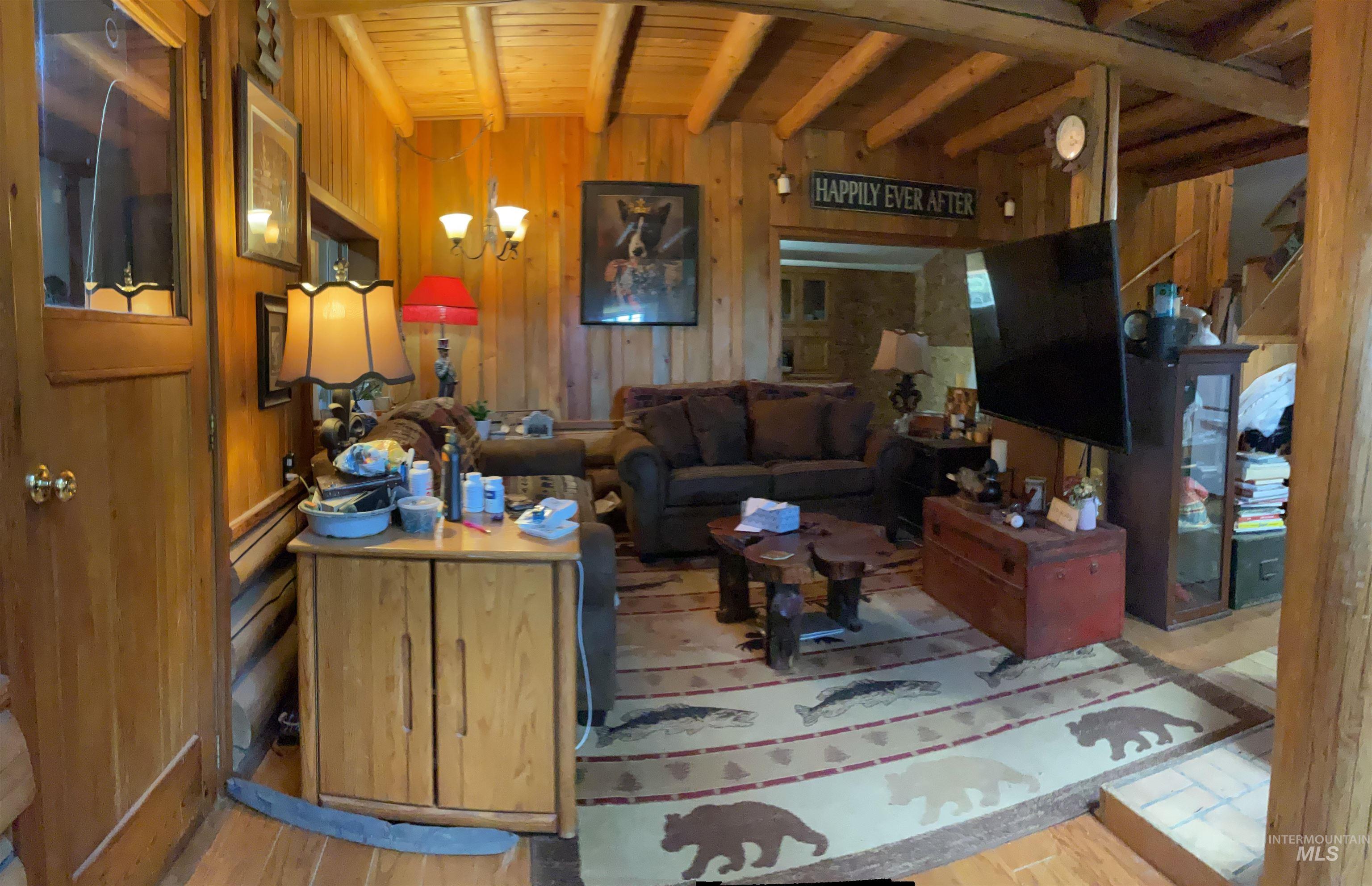 176 West Buffalo Gulch Road Elk City, ID 83525 - Photo 15 of 38 Living area featuring wood paneling, wood-finish flooring, exposed wood ceiling beams, and a built-in wall niche