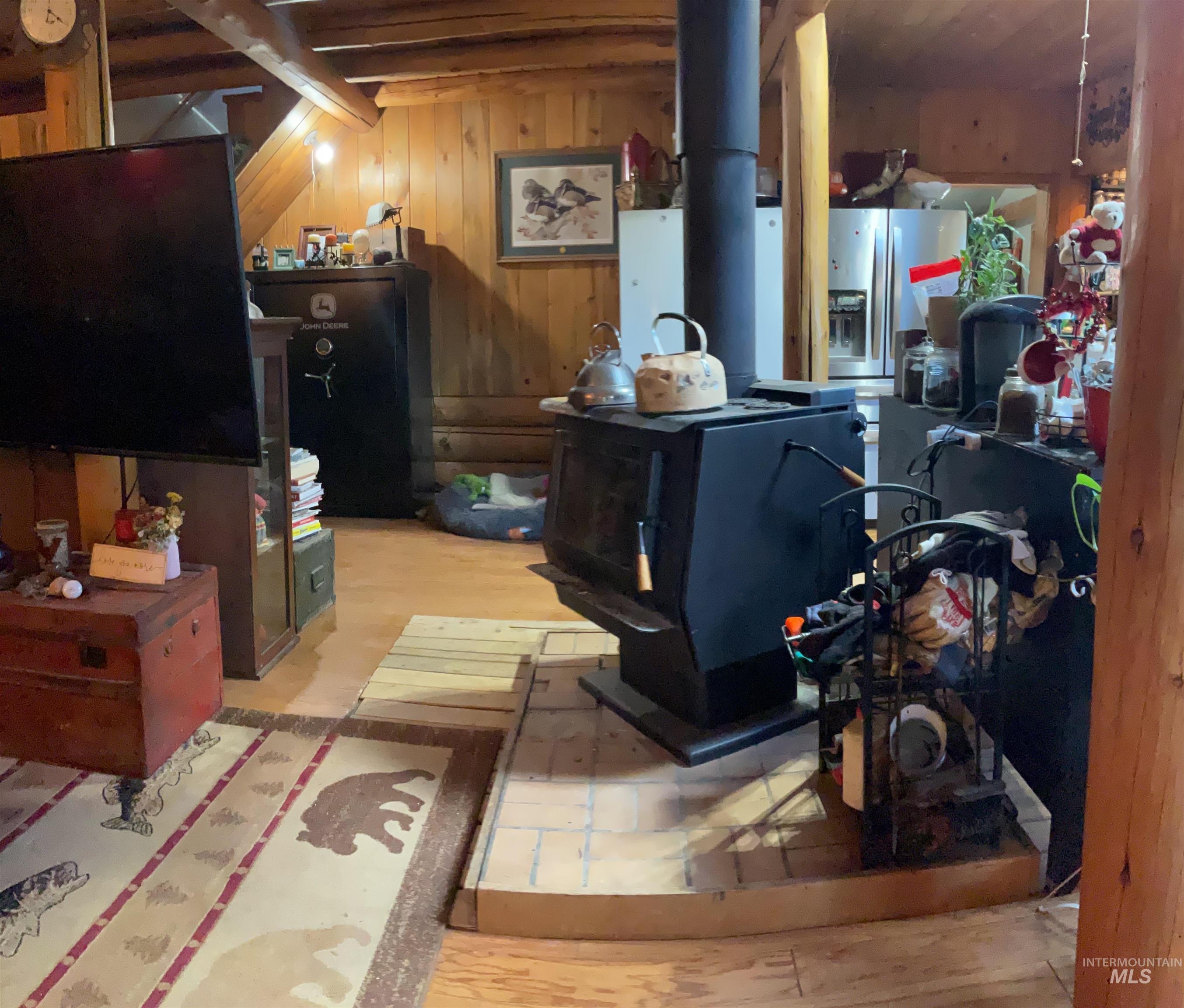 176 West Buffalo Gulch Road Elk City, ID 83525 - Photo 16 of 38 Wood-paneled interior featuring a black wood-burning stove with a brick-finish base
