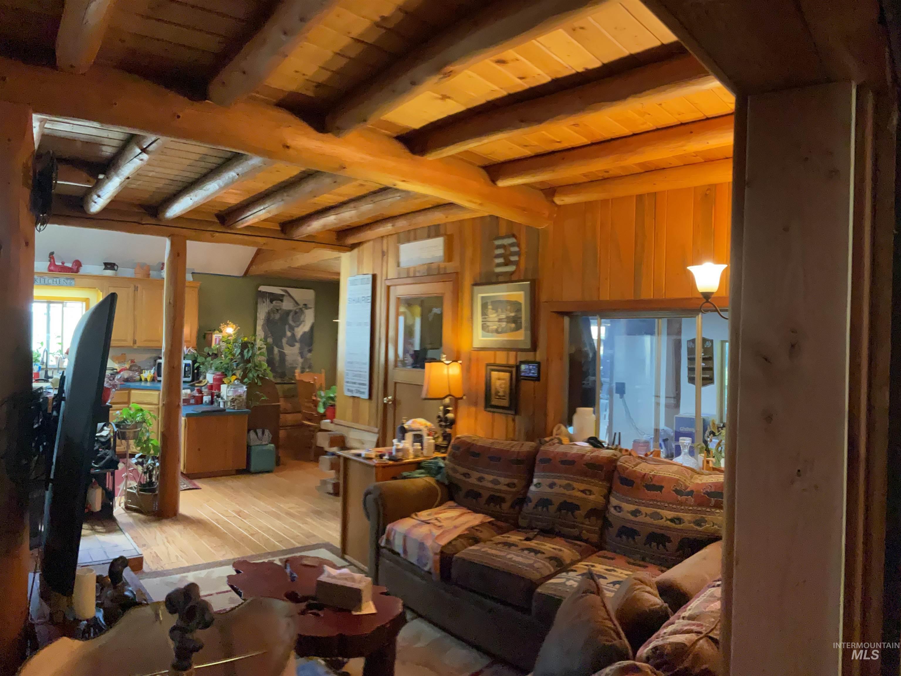 176 West Buffalo Gulch Road Elk City, ID 83525 - Photo 19 of 38 Exposed wood beam ceiling in a living area featuring wood-finish flooring and wood paneling