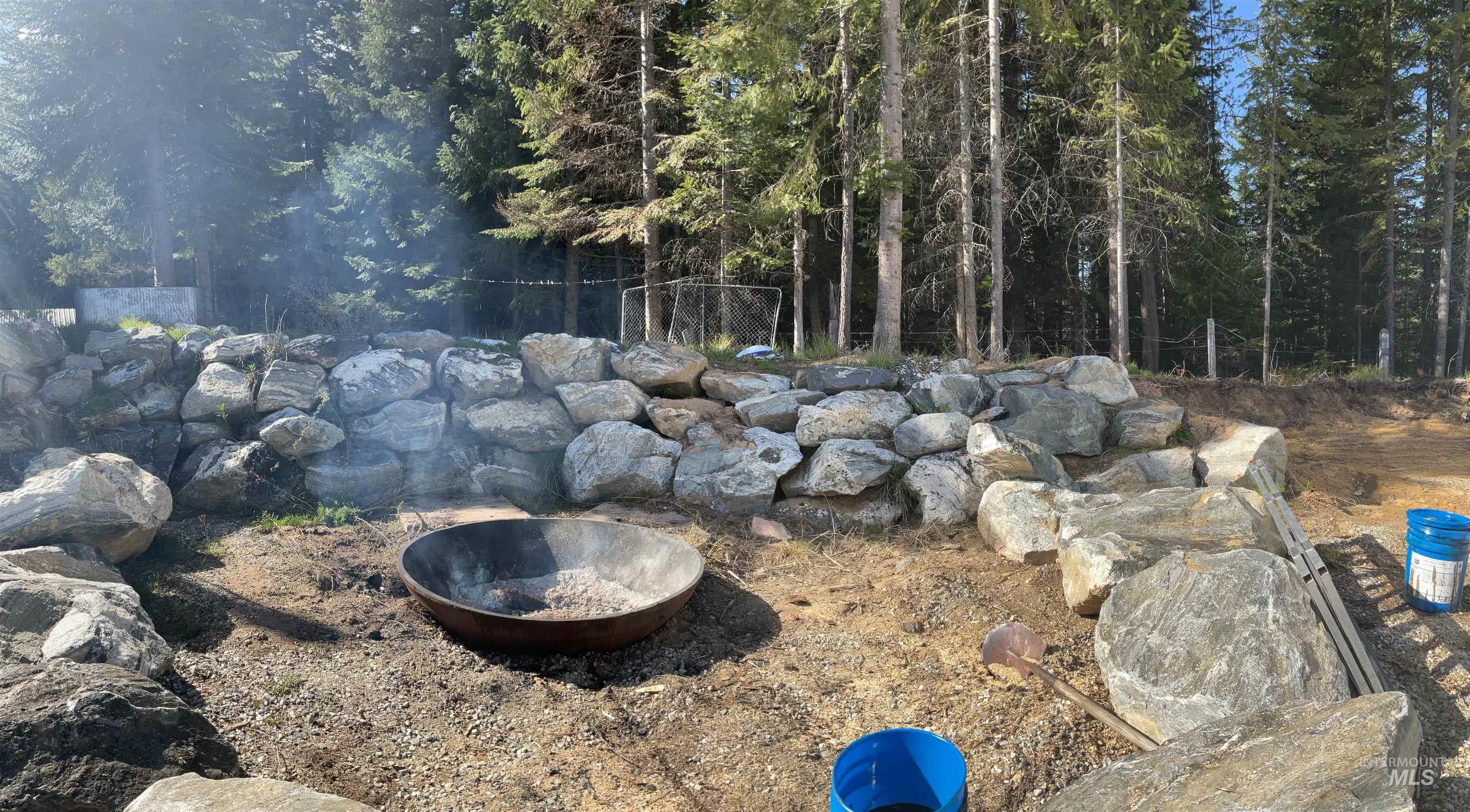 176 West Buffalo Gulch Road Elk City, ID 83525 - Photo 27 of 38 Outdoor fire pit area featuring a natural stone retaining wall and surrounding timberland