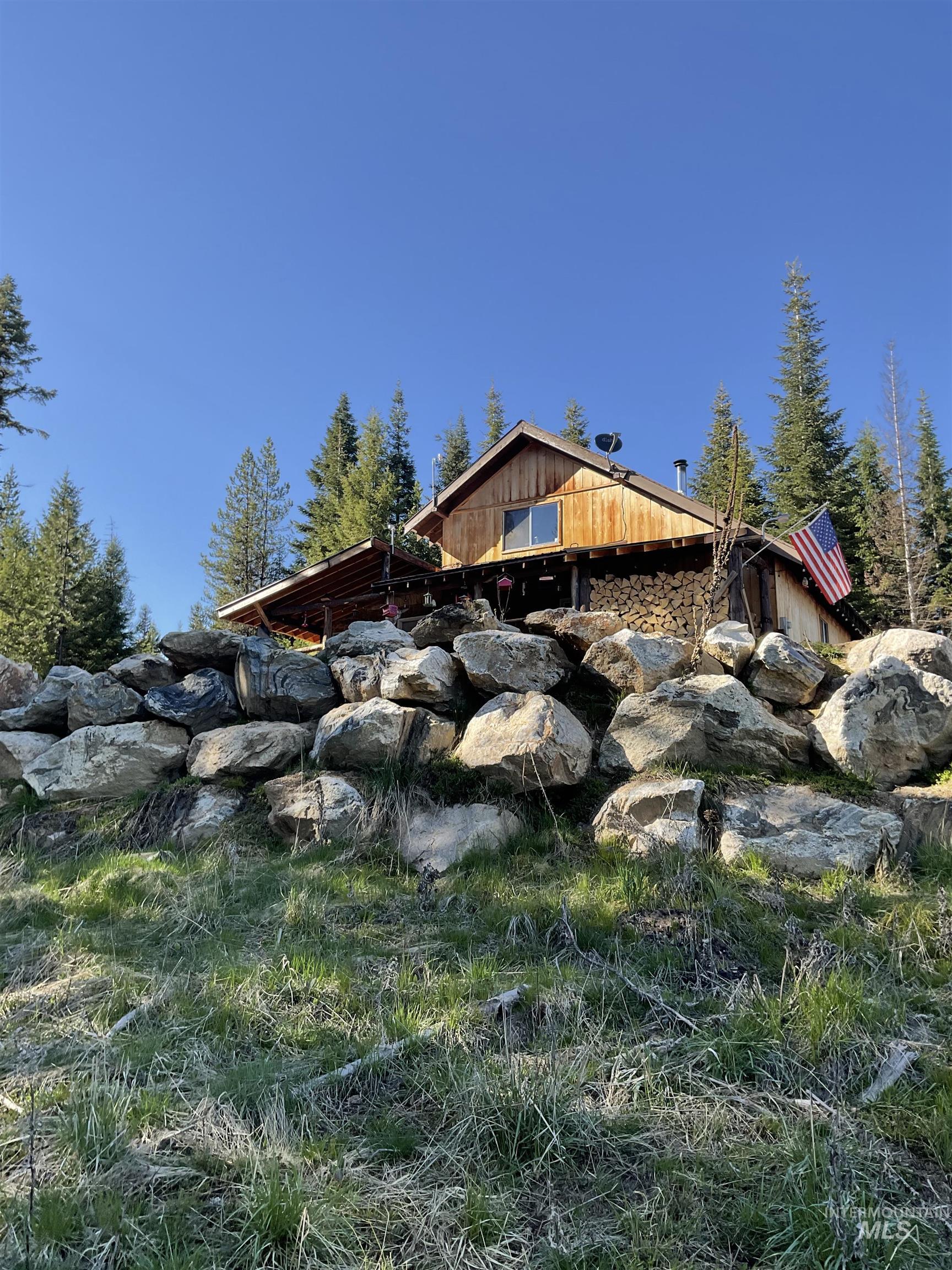 176 West Buffalo Gulch Road Elk City, ID 83525 - Photo 30 of 38 Wood-sided residence situated on a sloped lot with a natural rock retaining wall