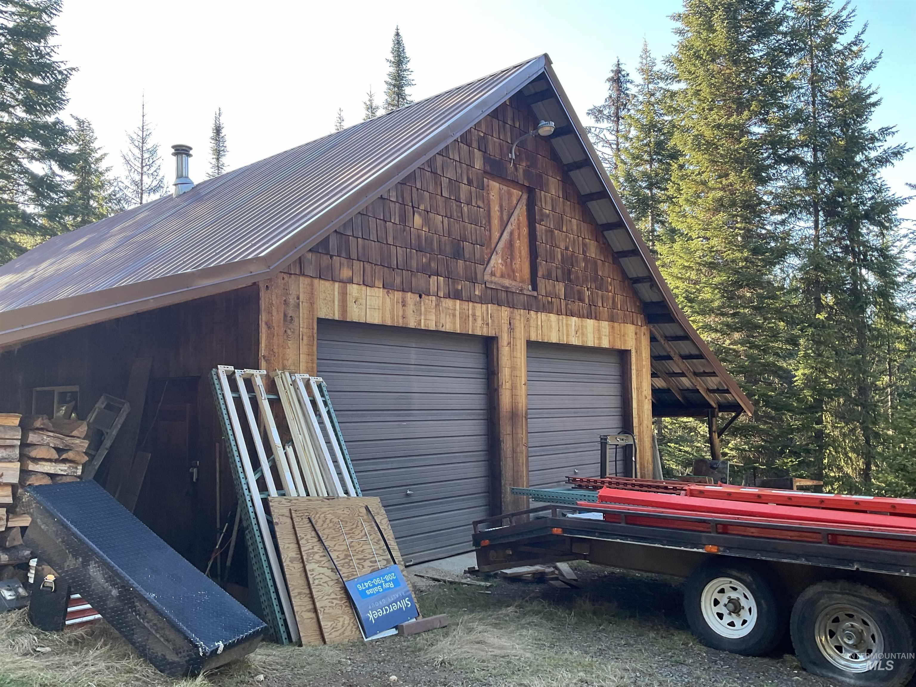 176 West Buffalo Gulch Road Elk City, ID 83525 - Photo 35 of 38 Freestanding structure featuring a brown corrugated metal roof, wood shingle siding, and two garage doors