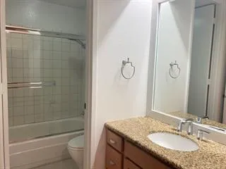 a bathroom with a granite countertop sink a toilet and shower
