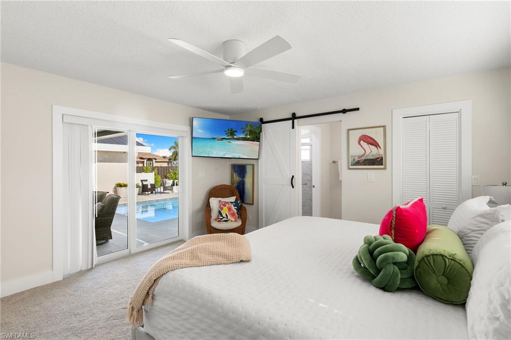 321 Columbus Way Marco Island, FL 34145 - Photo 18 of 40 Bedroom featuring a barn door, carpet floors, access to exterior, a closet, and ceiling fan