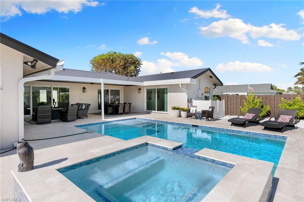 321 Columbus Way Marco Island, FL 34145 - Photo 24 of 40 Rear view of house featuring an outdoor hangout area, a patio area, stucco siding, a pool with connected hot tub, and a metal roof