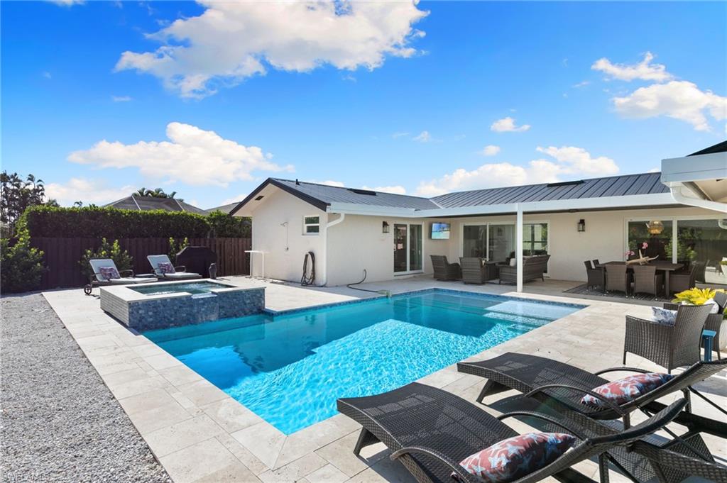 321 Columbus Way Marco Island, FL 34145 - Photo 27 of 40 View of swimming pool featuring outdoor lounge area, a patio, a fenced backyard, a pool with connected hot tub, and outdoor dining space
