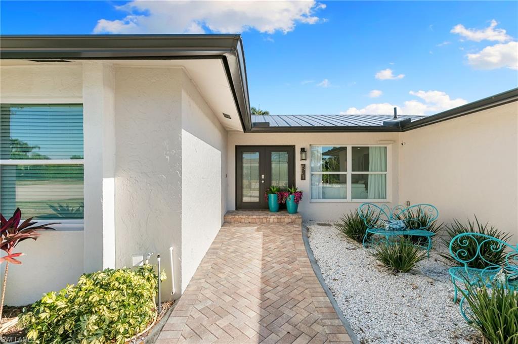 321 Columbus Way Marco Island, FL 34145 - Photo 32 of 40 Entrance to property with stucco siding, a metal roof, and french doors