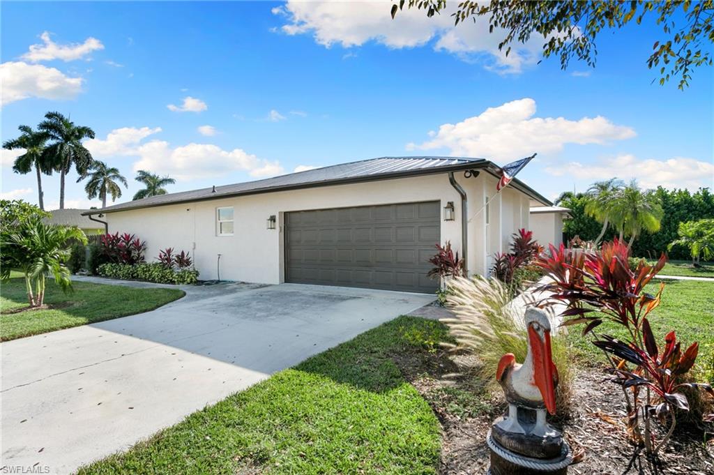 321 Columbus Way Marco Island, FL 34145 - Photo 33 of 40 View of front of home with concrete driveway, stucco siding, a garage, a front lawn, and a metal roof