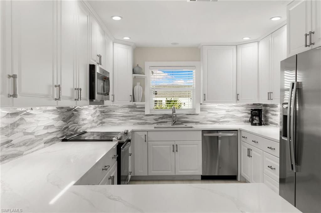 321 Columbus Way Marco Island, FL 34145 - Photo 10 of 40 Kitchen with stainless steel appliances, white cabinets, light stone countertops, backsplash, and recessed lighting