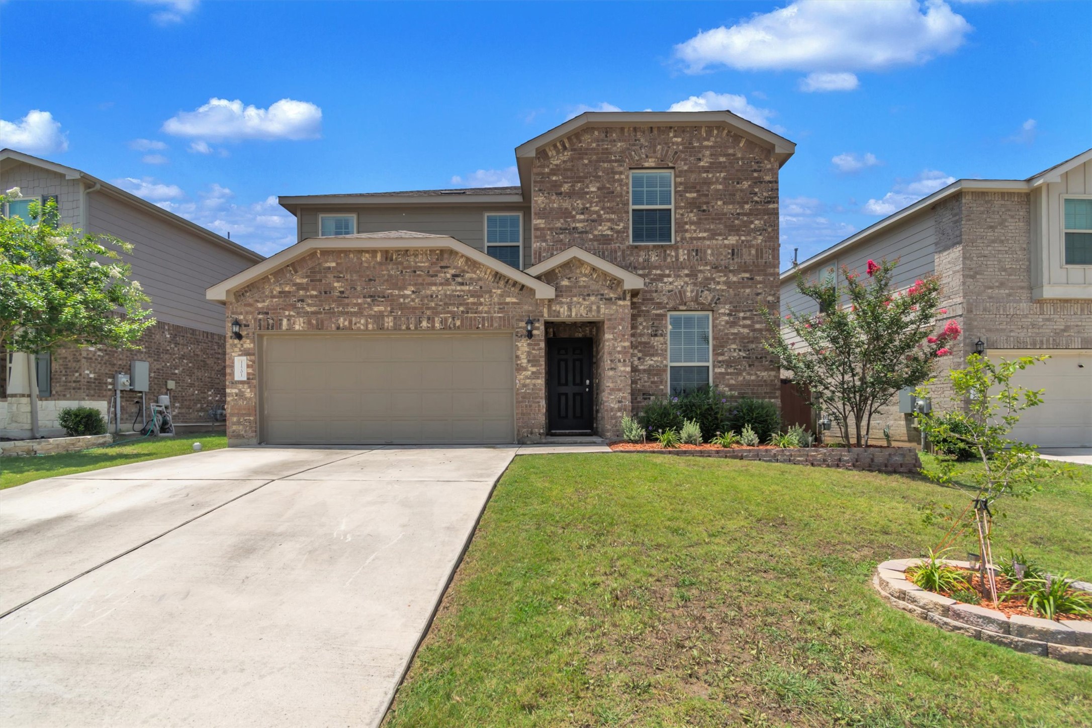 11701 Jackson Falls Way Manor, TX 78653 - Photo 3 of 40 Brick facade home featuring an integrated garage and a landscaped front yard.