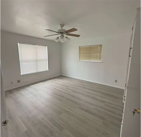 a view of empty room with wooden floor and fan