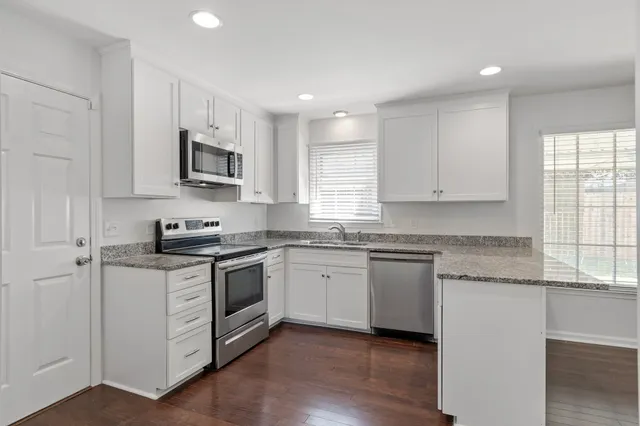 a kitchen with granite countertop white cabinets and white appliances