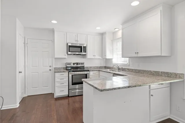 a kitchen with granite countertop white cabinets and stainless steel appliances