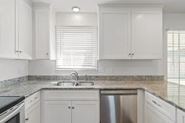 a kitchen with granite countertop white cabinets and a sink