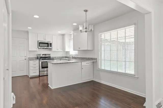 a kitchen with granite countertop a stove a sink a center island a refrigerator and a window