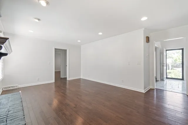 an empty room with wooden floor and windows with curtains
