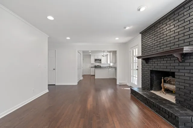 a living room with stainless steel appliances furniture a fireplace and wooden floor