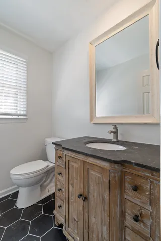 a bathroom with a granite countertop sink a toilet and a mirror