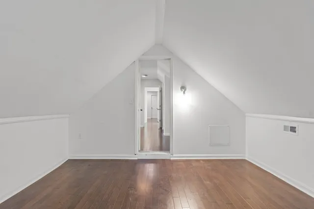 a view of an empty room with wooden floor and closet
