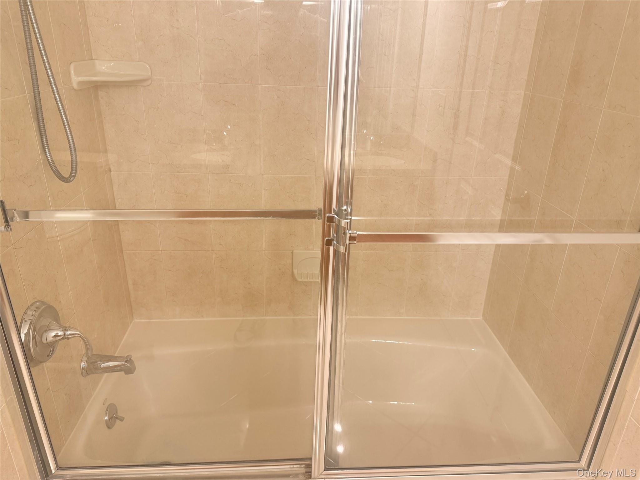 935 Tower Ridge Circle Middletown, NY 10941 - Photo 11 of 24 Bathtub and shower combination featuring neutral-toned wall tiling, chrome fixtures, and a clear glass shower enclosure with a sliding door