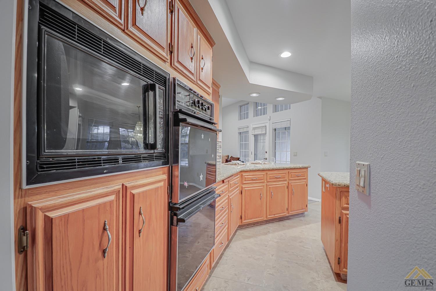Undisclosed Address Bakersfield, CA 93314 - Photo 11 of 38 a kitchen with granite countertop a refrigerator and white cabinets
