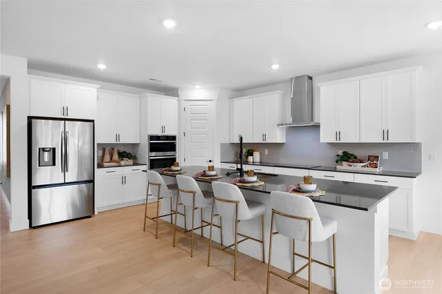 a kitchen with stainless steel appliances granite countertop a stove a sink a refrigerator and white cabinets