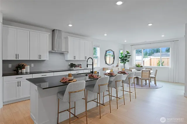 a kitchen with stainless steel appliances granite countertop a stove a sink a dining table and chairs with wooden floor