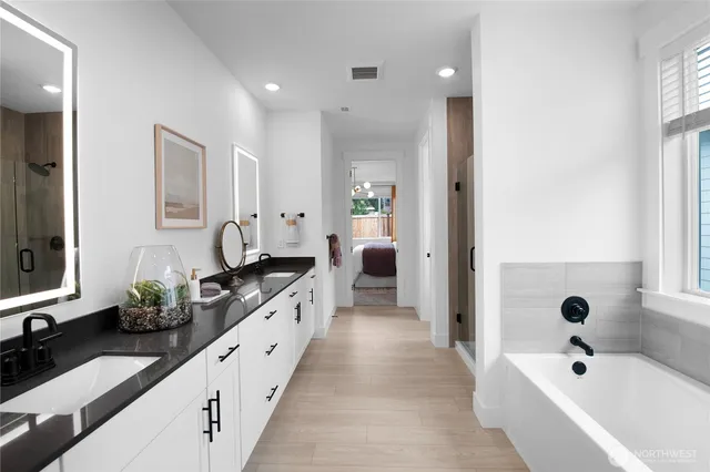 a large white bathroom with a bathtub a double vanity sink and mirror