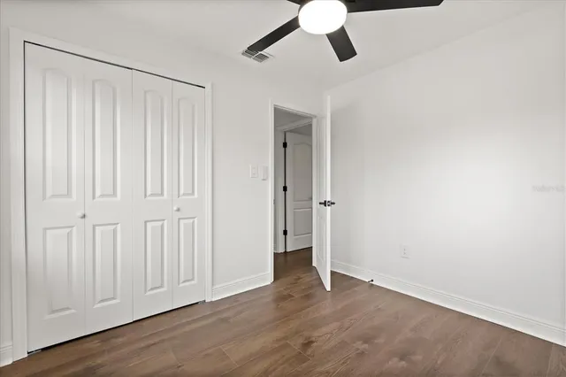 an empty room with wooden floor cabinet and windows