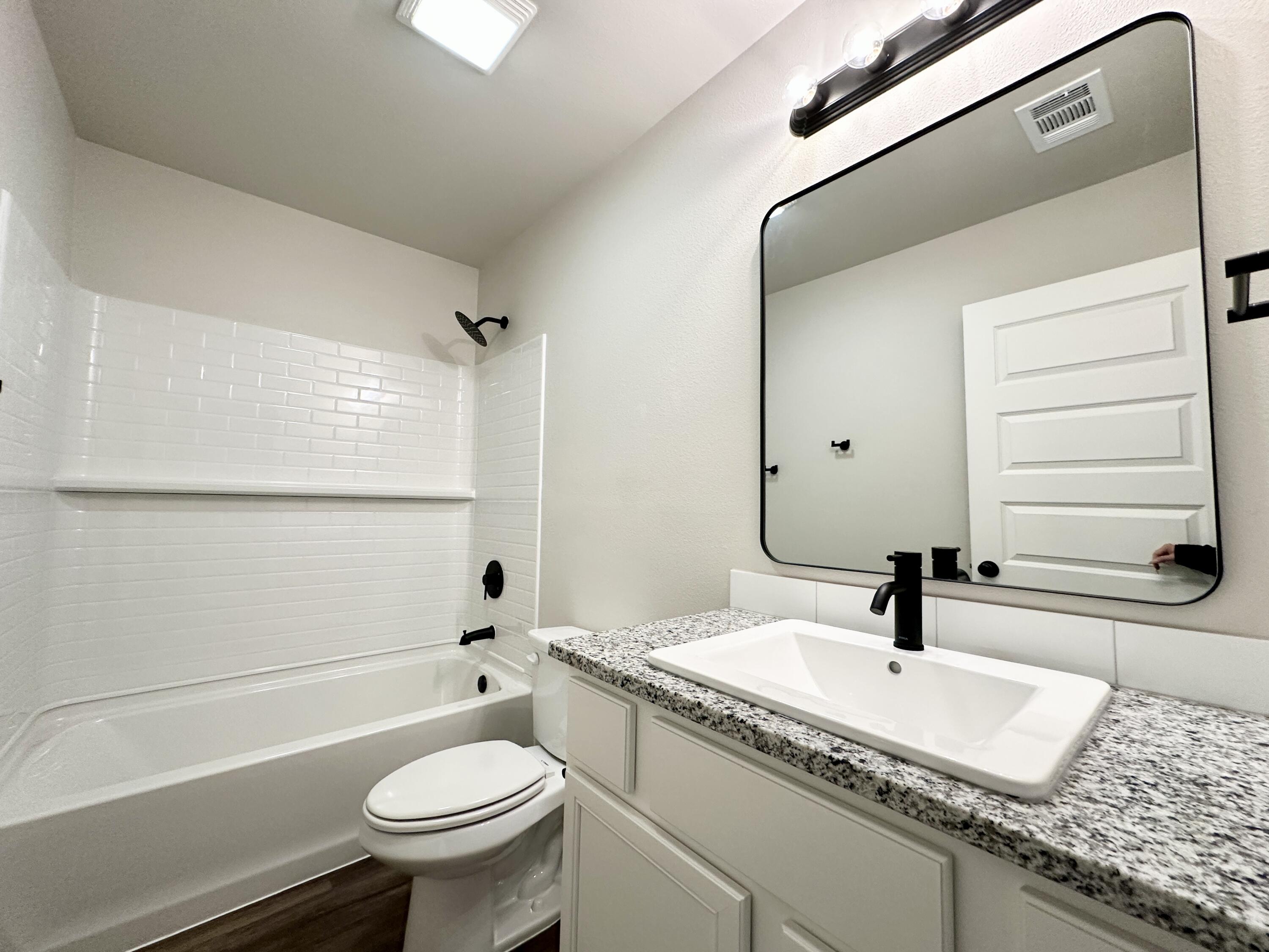 7449 28th Street Lubbock, TX 79407 - Photo 7 of 11 a bathroom with a granite countertop sink toilet a mirror and shower