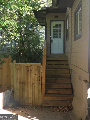 a view of house with wooden fence and large trees