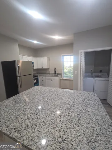 a large kitchen with kitchen island sink refrigerator and cabinets