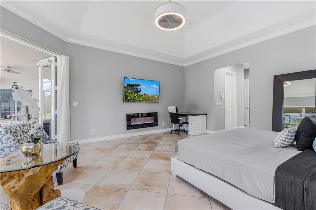 160 Logan Boulevard South Naples, FL 34119 - Photo 14 of 49 Bedroom featuring multiple windows, a desk, crown molding, a glass covered fireplace, and access to outside