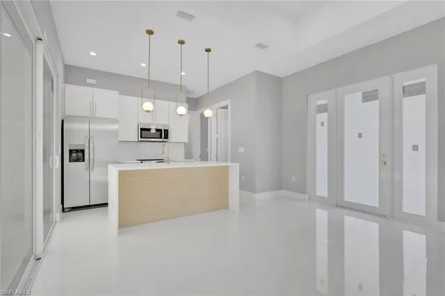 a view of a kitchen with refrigerator and white cabinets