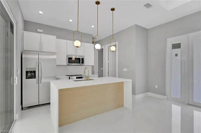 a kitchen with kitchen island a stove a refrigerator a sink and a oven with wooden floor