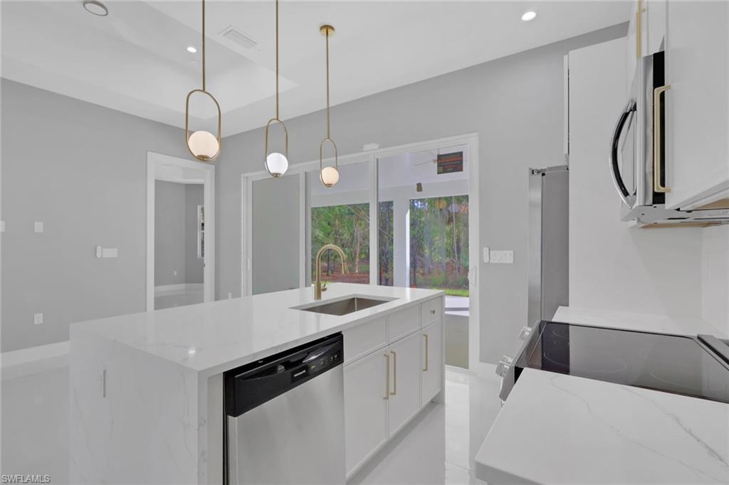 160 Logan Boulevard South Naples, FL 34119 - Photo 36 of 49 Kitchen featuring white cabinetry, stainless steel appliances, decorative light fixtures, recessed lighting, and light stone countertops