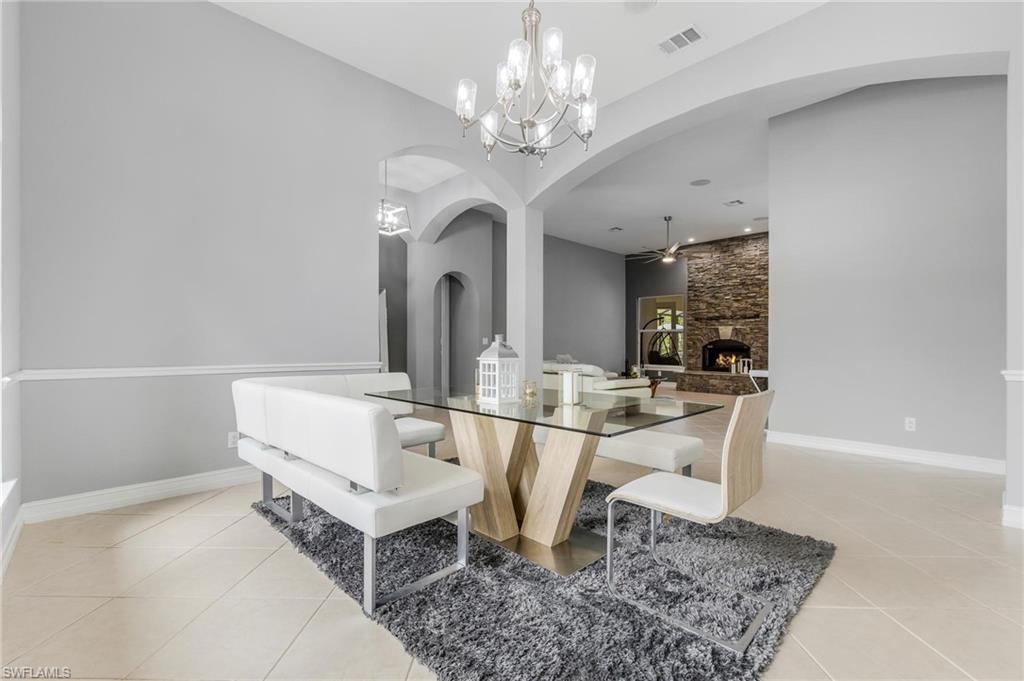 160 Logan Boulevard South Naples, FL 34119 - Photo 6 of 49 Dining space featuring arched walkways, a fireplace, a chandelier, and light tile patterned floors