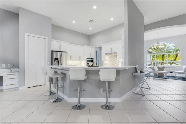 a living room with couches a coffee table and kitchen view with wooden floor