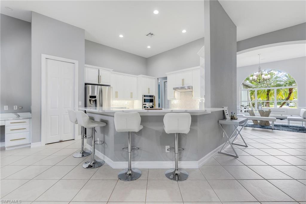160 Logan Boulevard South Naples, FL 34119 - Photo 8 of 49 Kitchen featuring a kitchen breakfast bar, white cabinetry, stainless steel refrigerator with ice dispenser, a chandelier, and recessed lighting