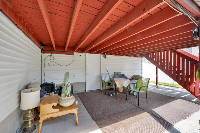 8029 Angel Street Sandy, UT 84070 - Photo 19 of 21 Under-deck concrete patio with a red-painted exposed beam ceiling and white vinyl siding