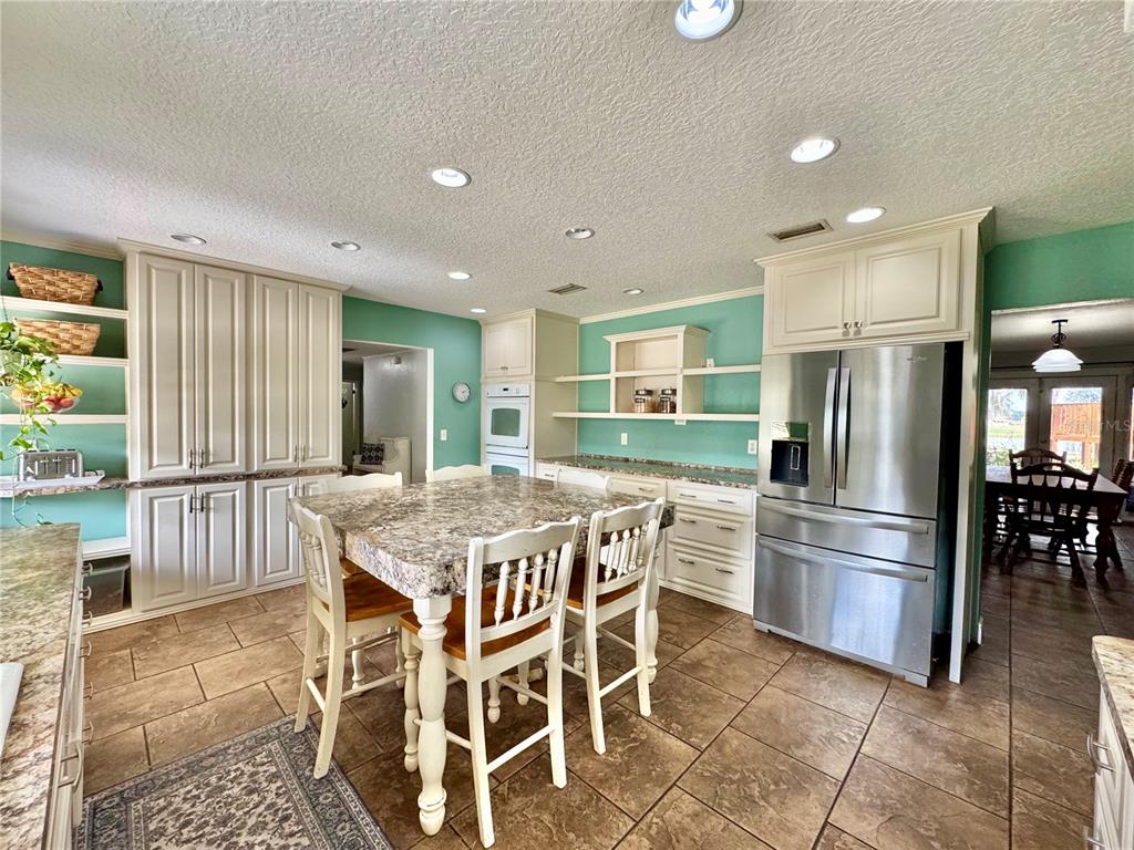 7625 East Misty Lane Inverness, FL 34450 - Photo 20 of 58 a kitchen with stainless steel appliances granite countertop a stove a refrigerator a oven a sink with a dining table and chairs