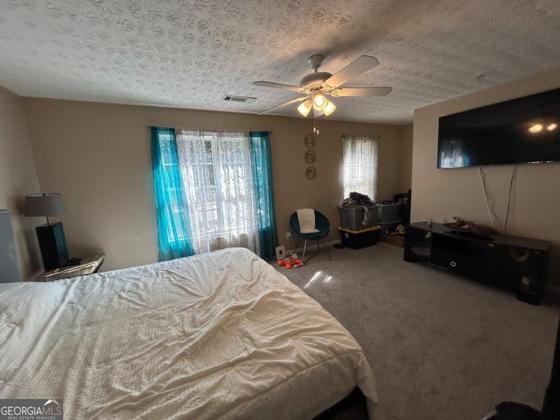 5099 Leeshire Trace Tucker, GA 30084 - Photo 15 of 26 a bedroom with a bed and a flat tv screen on dresser