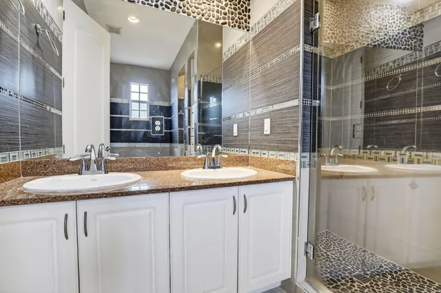 a bathroom with a granite countertop sink a mirror and shower