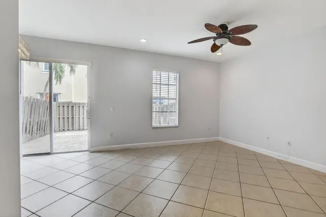 an empty room with windows and chandelier fan
