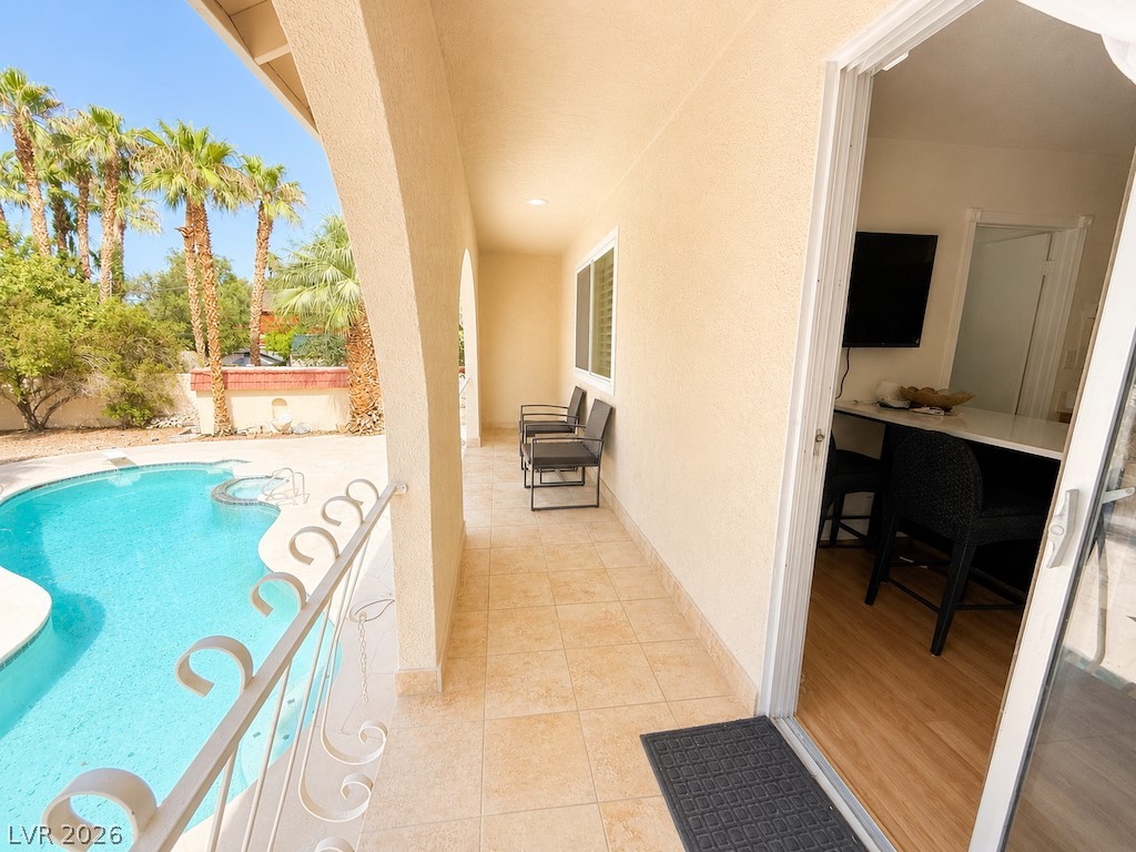 3010 East Viking Road Las Vegas, NV 89121 - Photo 40 of 48 A tranquil covered balcony overlooking a pristine pool, framed by lush palm trees.