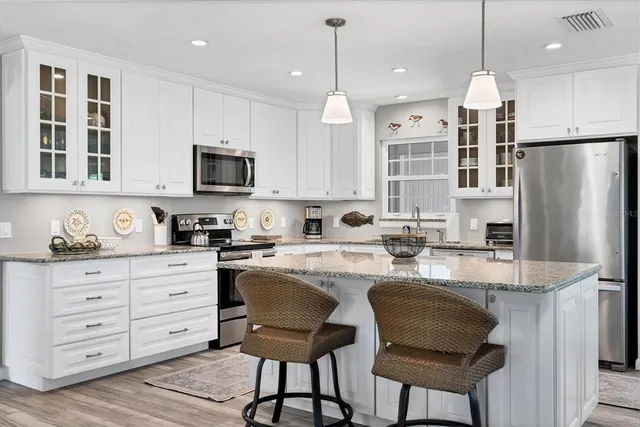 a kitchen with kitchen island granite countertop a stove a sink a center island and cabinets