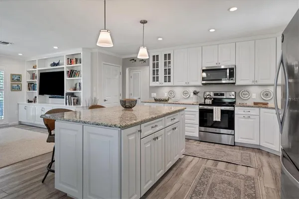 a kitchen with kitchen island granite countertop a stove top oven a sink dishwasher a dining table and chairs with wooden floor