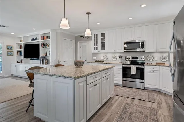 a kitchen with kitchen island granite countertop a stove top oven a sink dishwasher a dining table and chairs with wooden floor