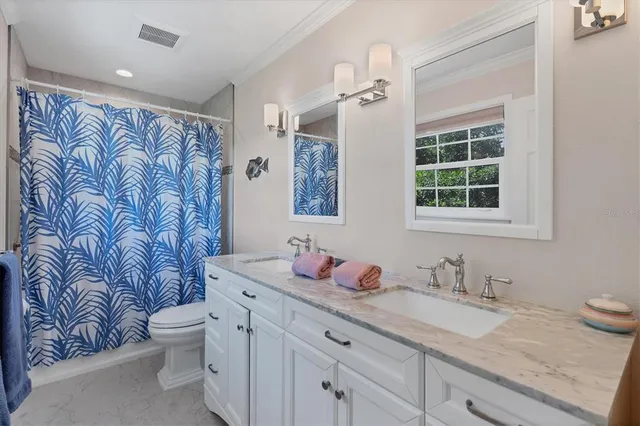 a bathroom with a granite countertop sink and mirror with toilet